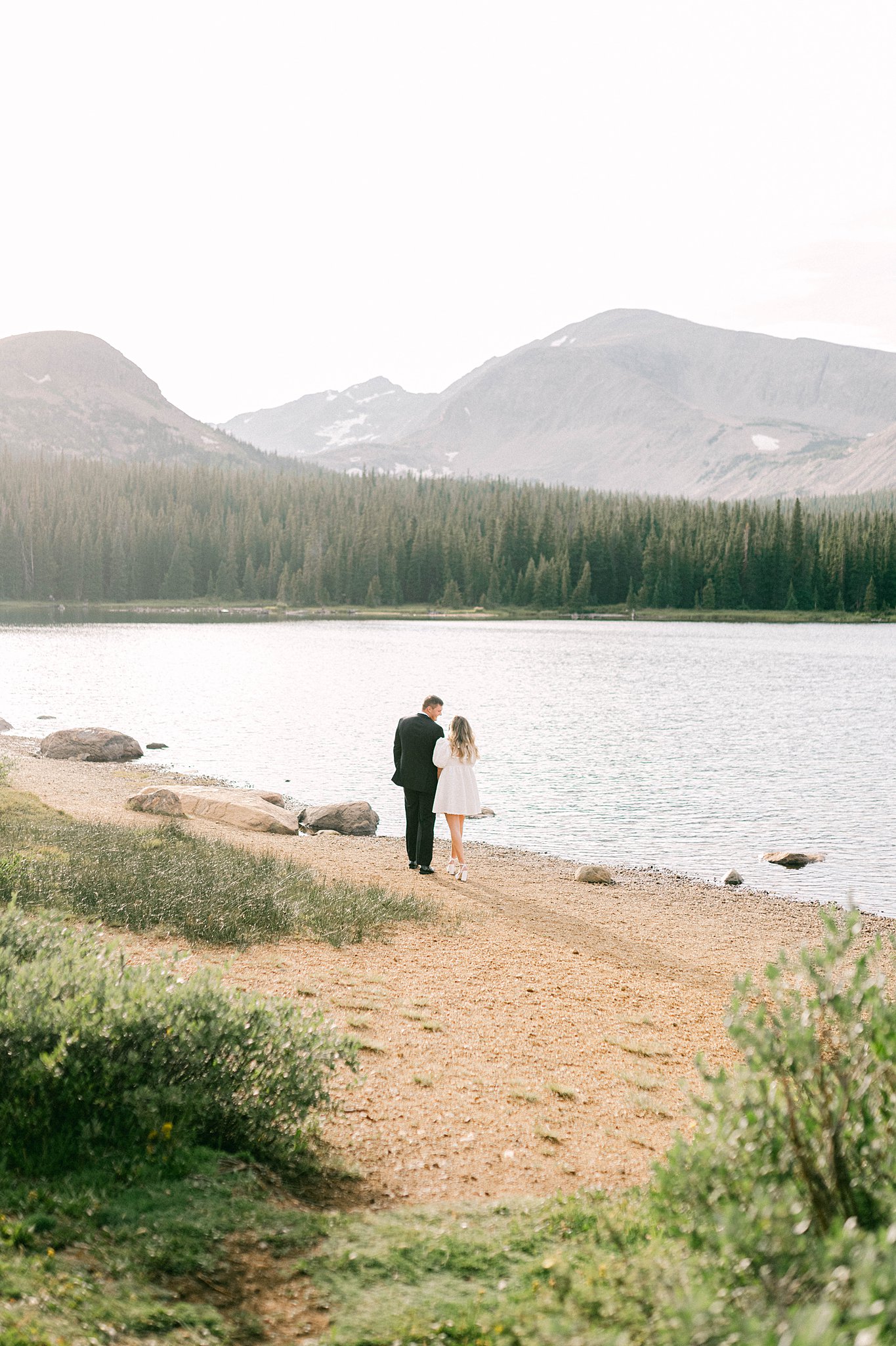 A couple walk hand in hand towards Brainard Lake during engagement session in Colorado