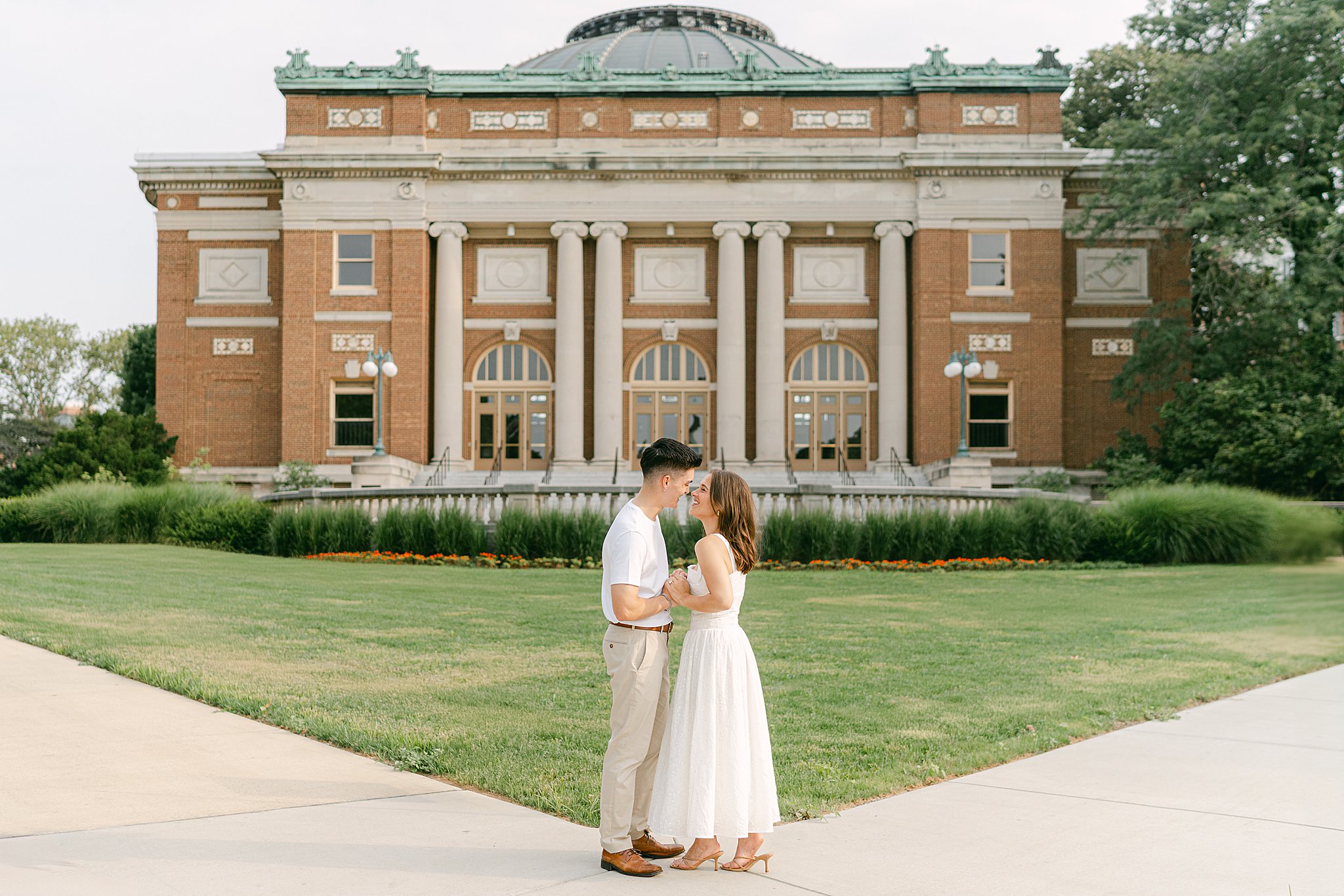 Kali and Zack embracing in front of the stunning architecture of Foellinger Auditorium at the University of Illinois