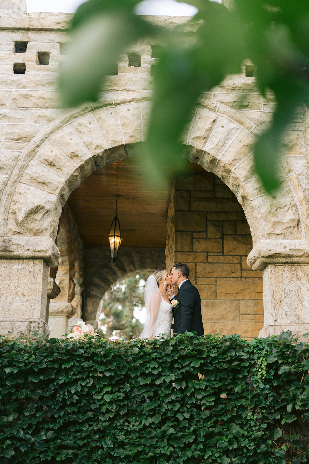 Bride and groom kiss under the stone arch of the Haley Mansion in Joliet, Illinois